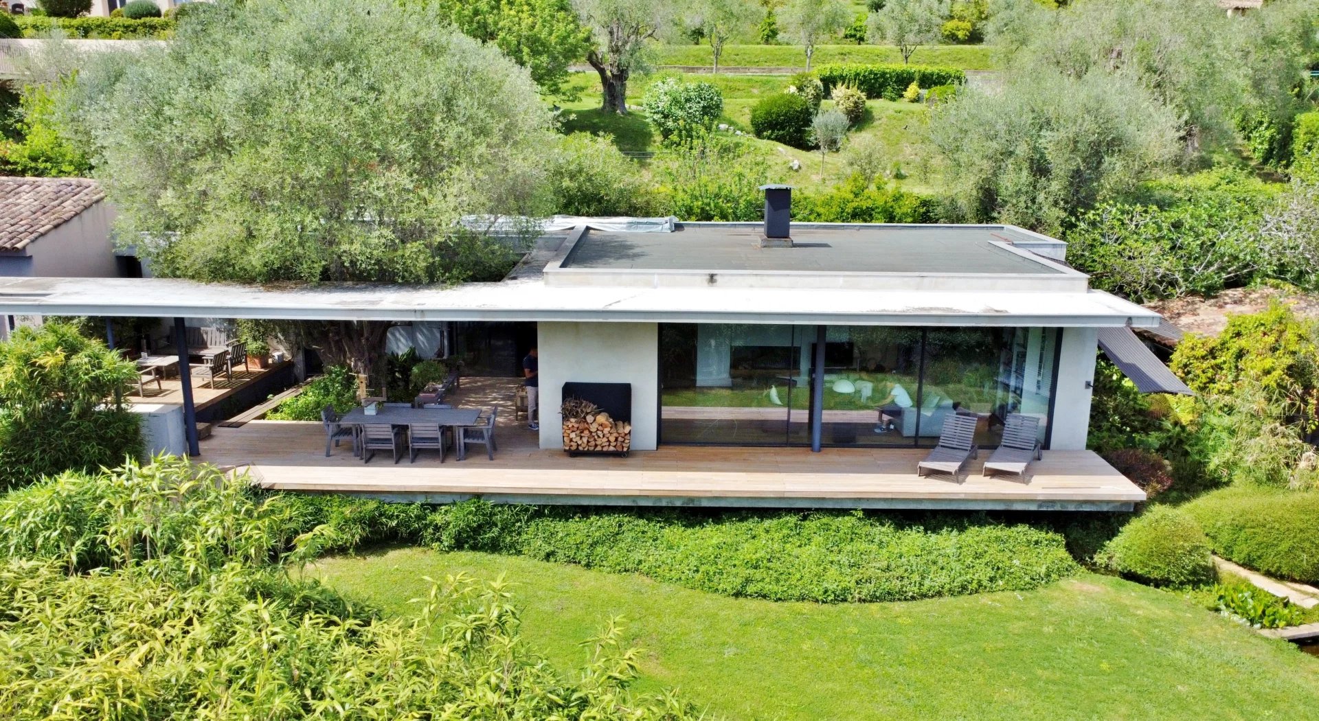 Villa Contemporaine entourée de verdure avec de grandes fenêtres et un jardin fleuri.