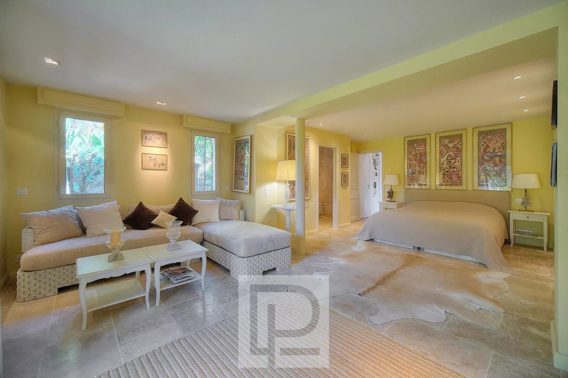 Une chambre lumineuse avec un grand lit, des murs jaunes et un coin salon confortable.