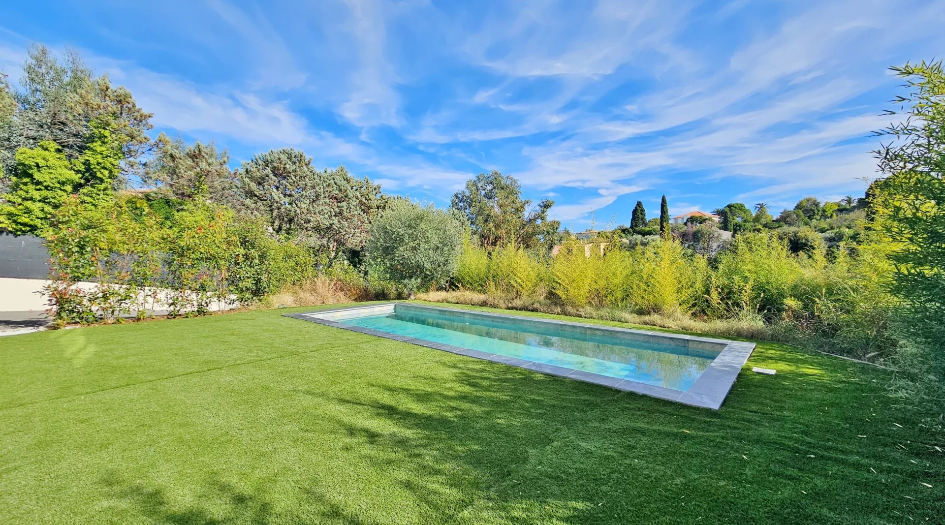 Une Villa Contemporaine avec piscine et jardin sous un ciel bleu.