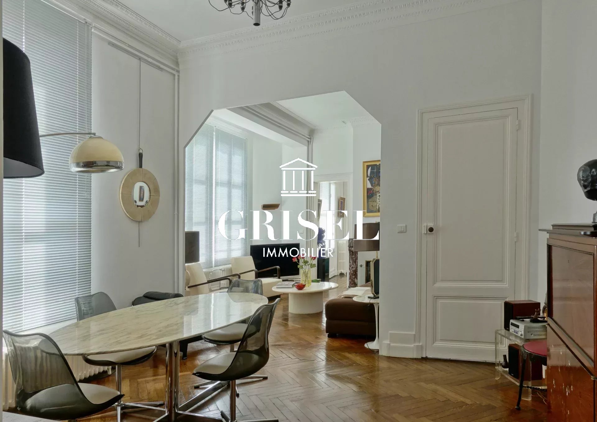 Salle à manger élégante avec table en marbre, chaises contemporaines et grandes fenêtres laissant entrer beaucoup de lumière naturelle.
