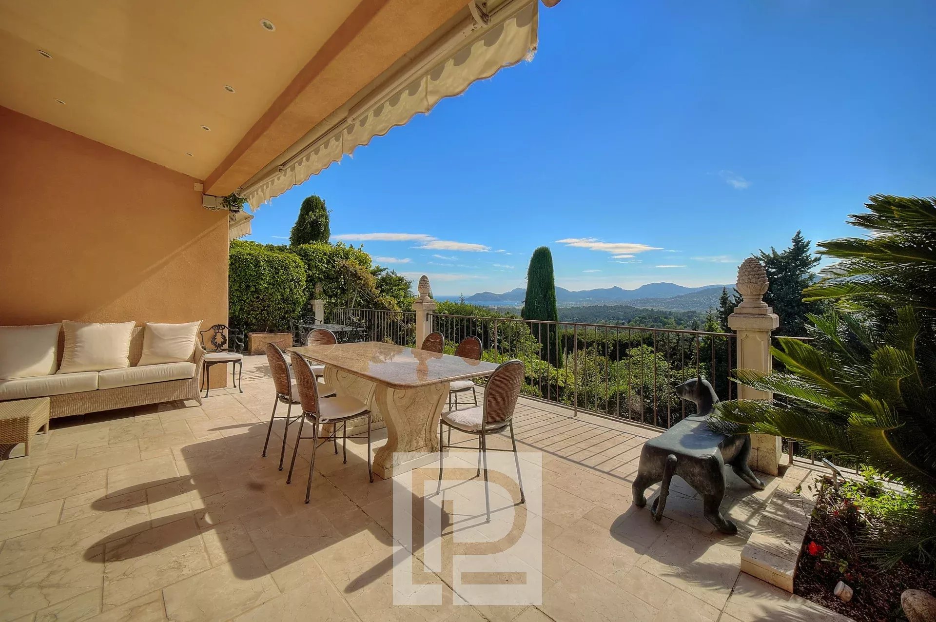 Une terrasse spacieuse avec des meubles élégants offrant une vue panoramique sur les collines et le ciel bleu.