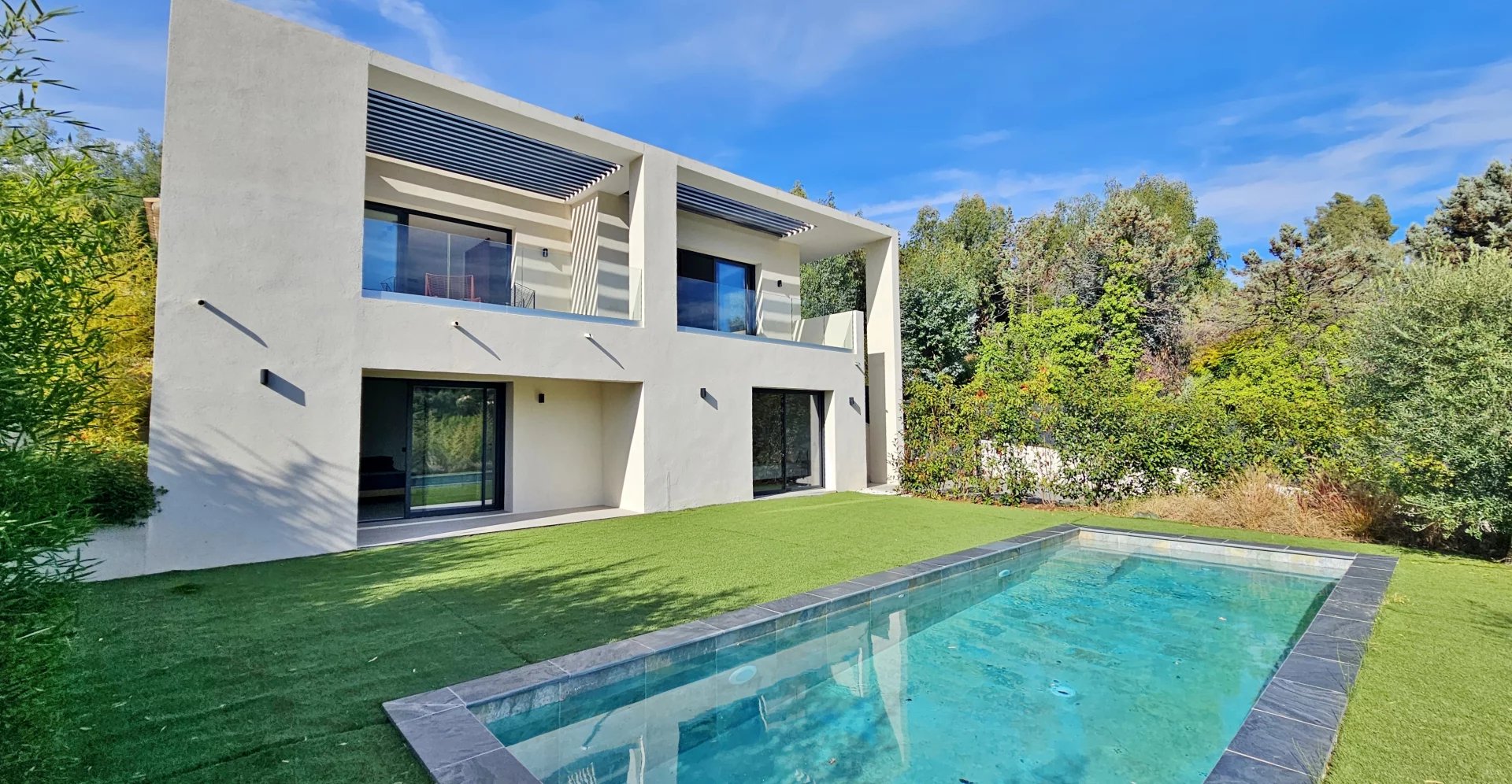 Une Villa Contemporaine avec piscine et jardin sous un ciel bleu.