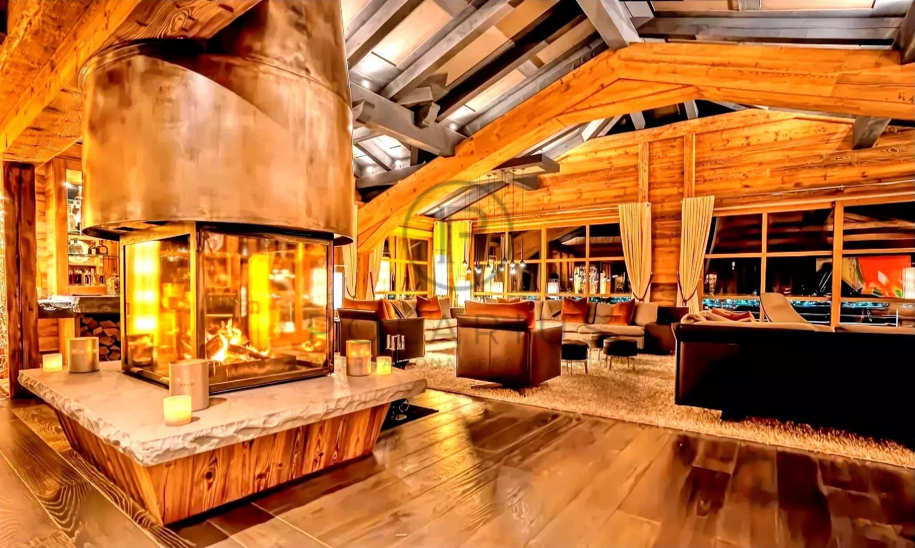 Un salon chaleureux avec une grande cheminée centrale et des fenêtres offrant une vue panoramique.