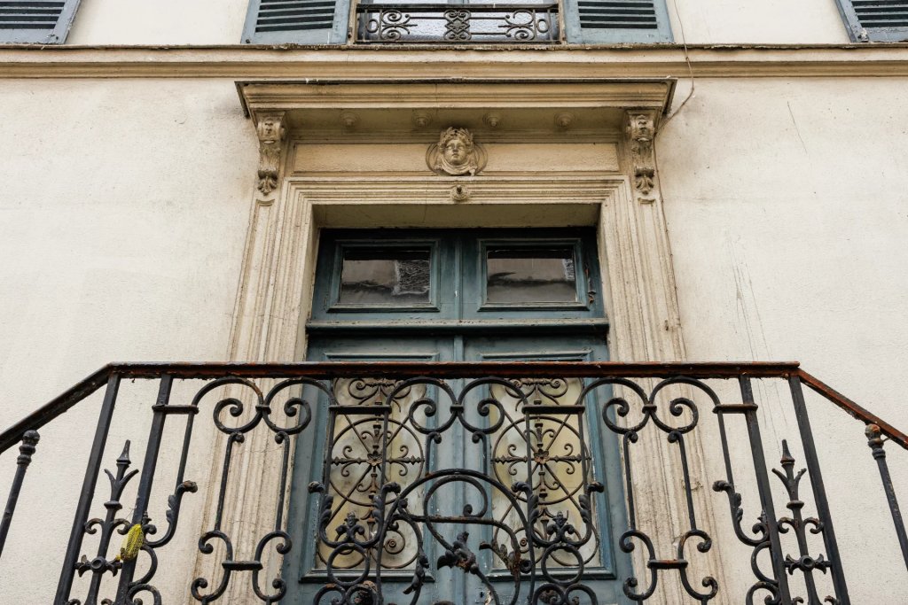 Mascaron sculpté et ferronnerie au-dessus de la porte d’entrée