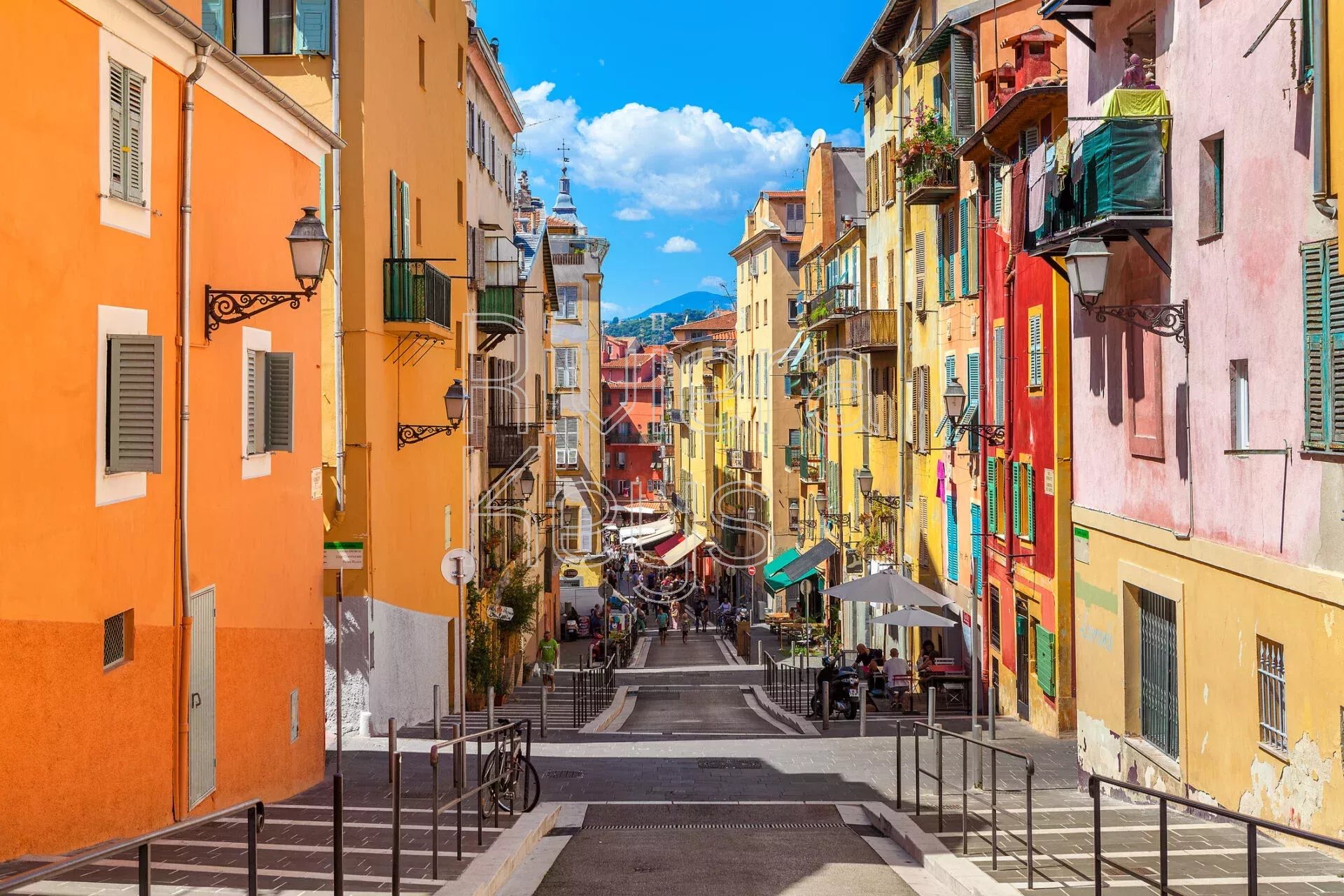 NICE, FRANCE - AUGUST 23, 2014: Narrow street in old tourist part of Nice - fifth most populous city and one of the most visited cities in France, receiving 4 million tourists every year. (NICE, FRANC