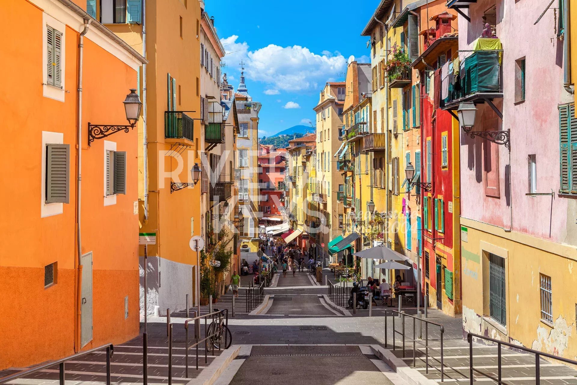 NICE, FRANCE - AUGUST 23, 2014: Narrow street in old tourist part of Nice - fifth most populous city and one of the most visited cities in France, receiving 4 million tourists every year. (NICE, FRANC