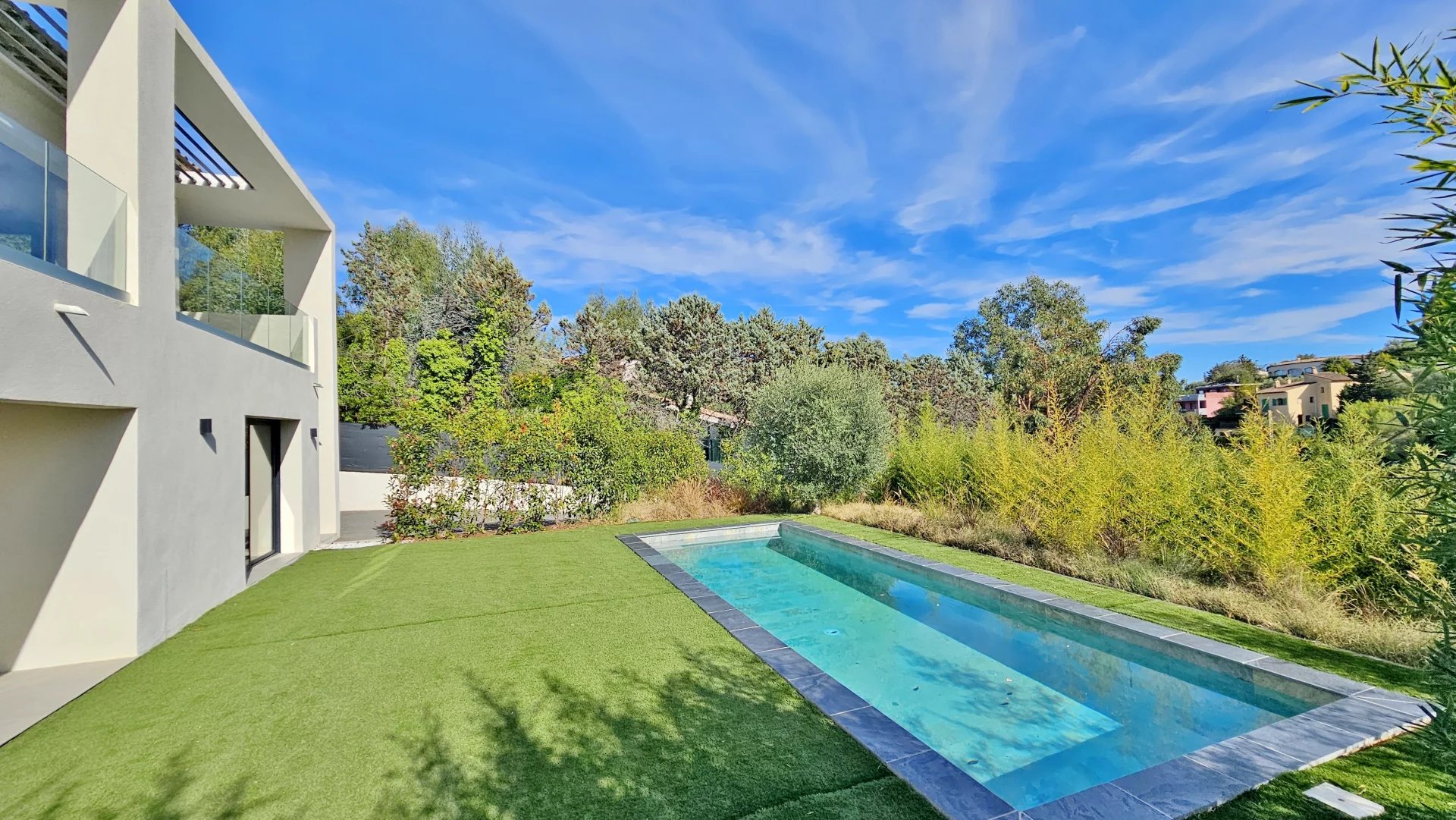 Une Villa Contemporaine avec piscine et jardin sous un ciel bleu.