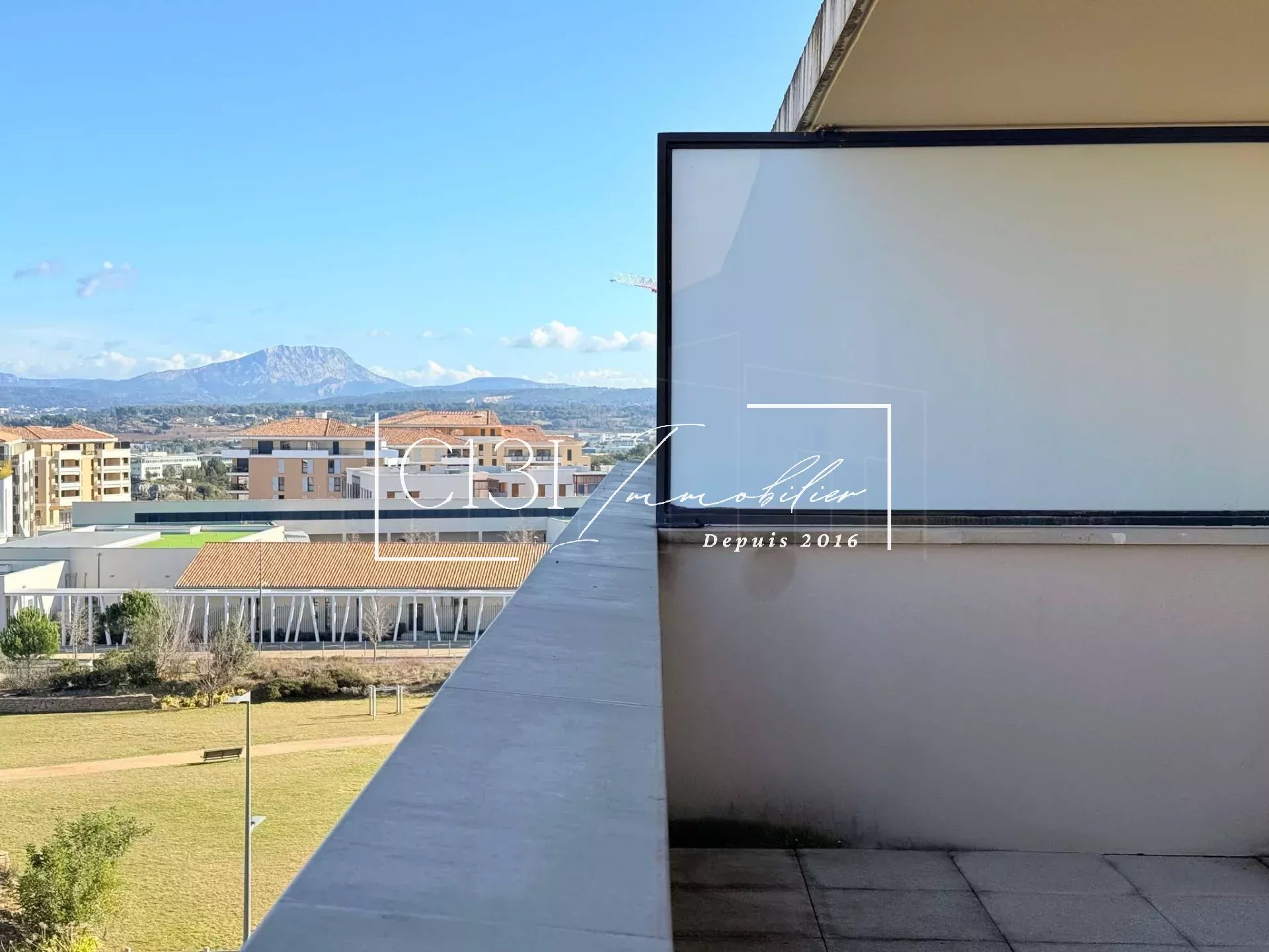 A balcony with a view overlooking a cityscape and distant mountains under a clear blue sky.