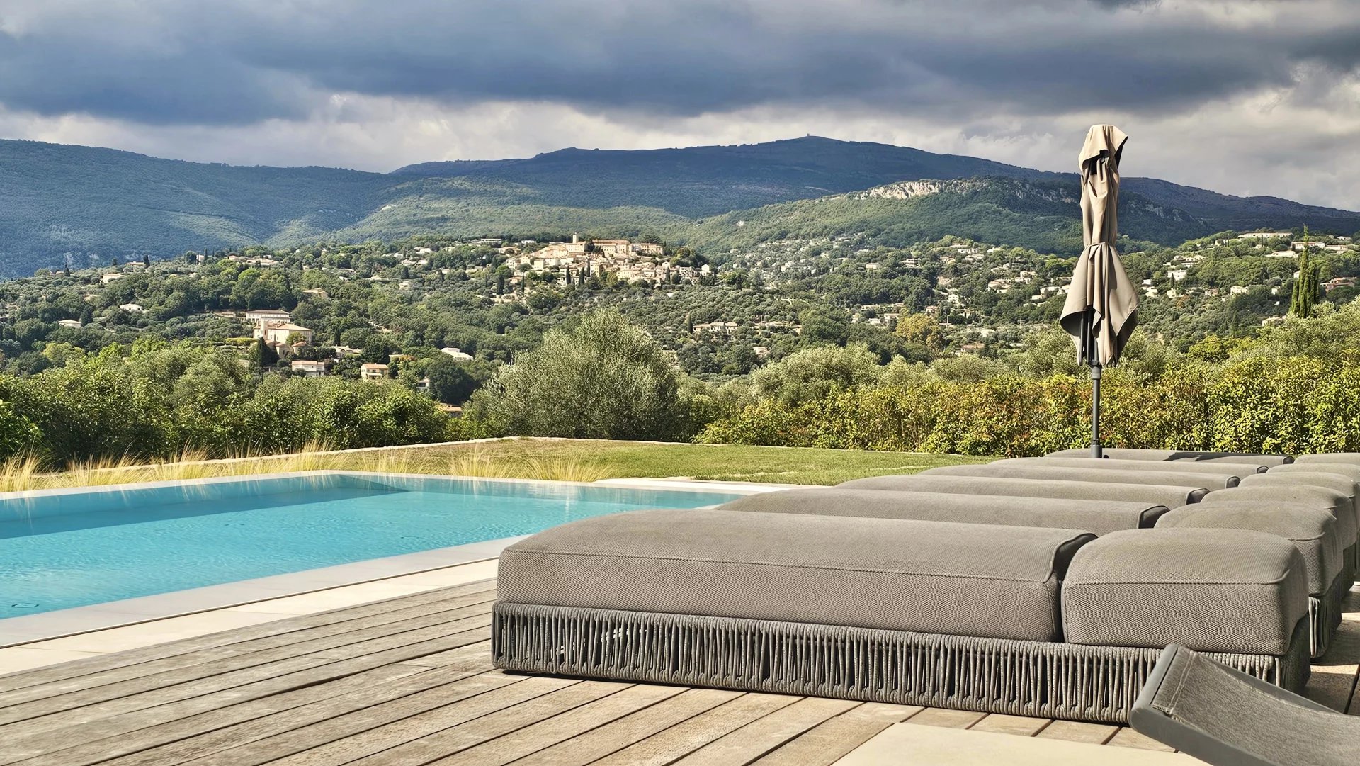 Belle maison moderne avec piscine, entourée de verdure, sous un ciel ensoleillé.