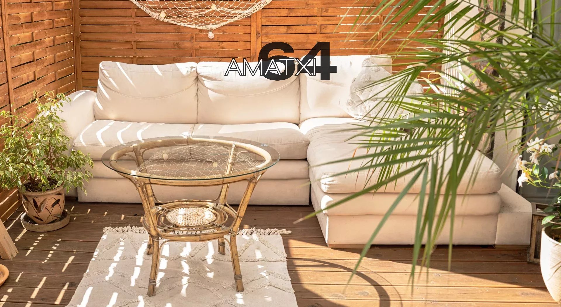 Real photo of relaxing boho zone in home. Wooden floor on terrace with comfy furniture and green plants. Decoration concept. Sunny summer day.
