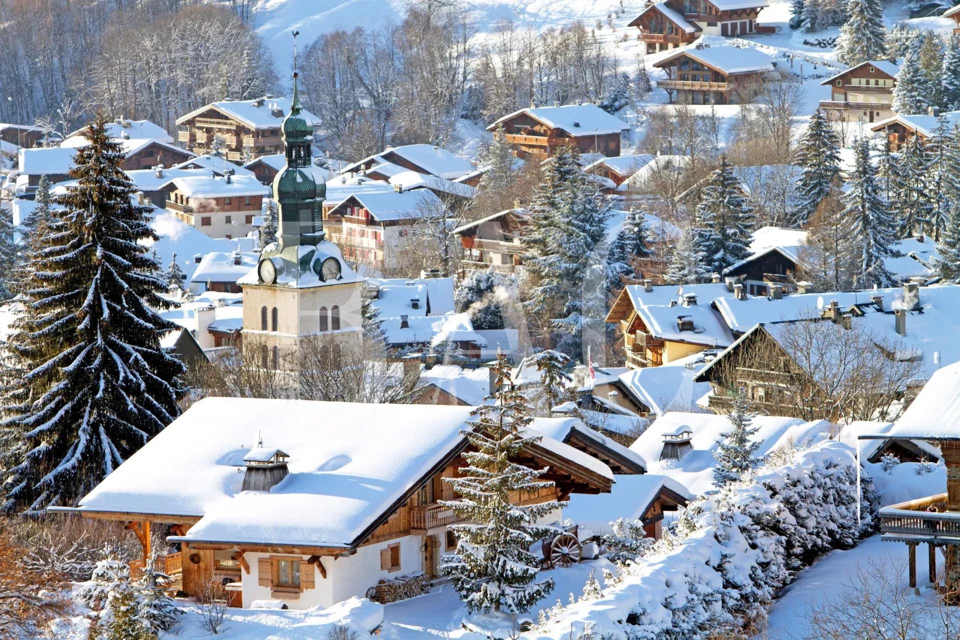 Megeve, a picturesque, snowy Alpine village with wooden chalets and a church tower.