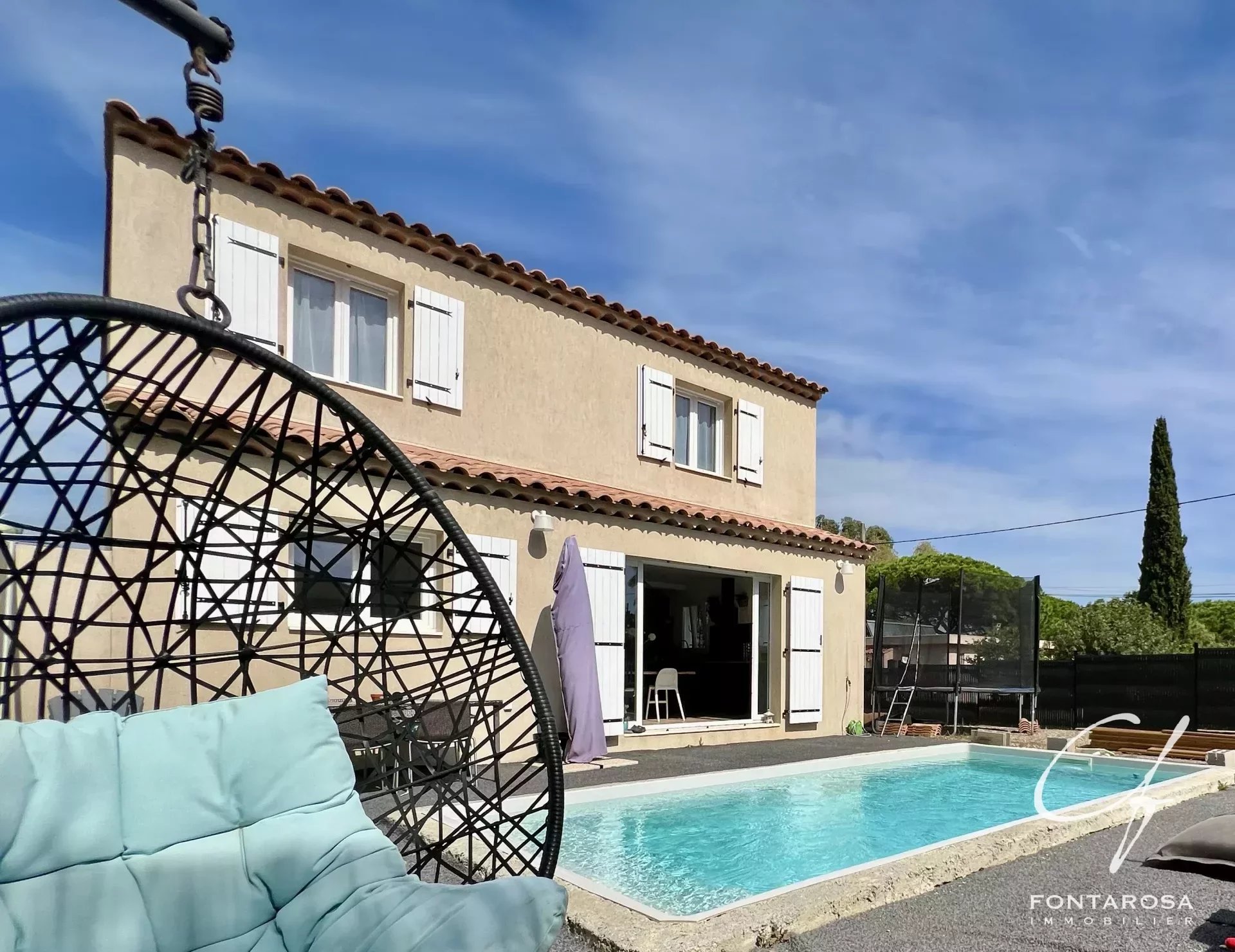 Maison moderne avec piscine et fauteuil suspendu en plein air.