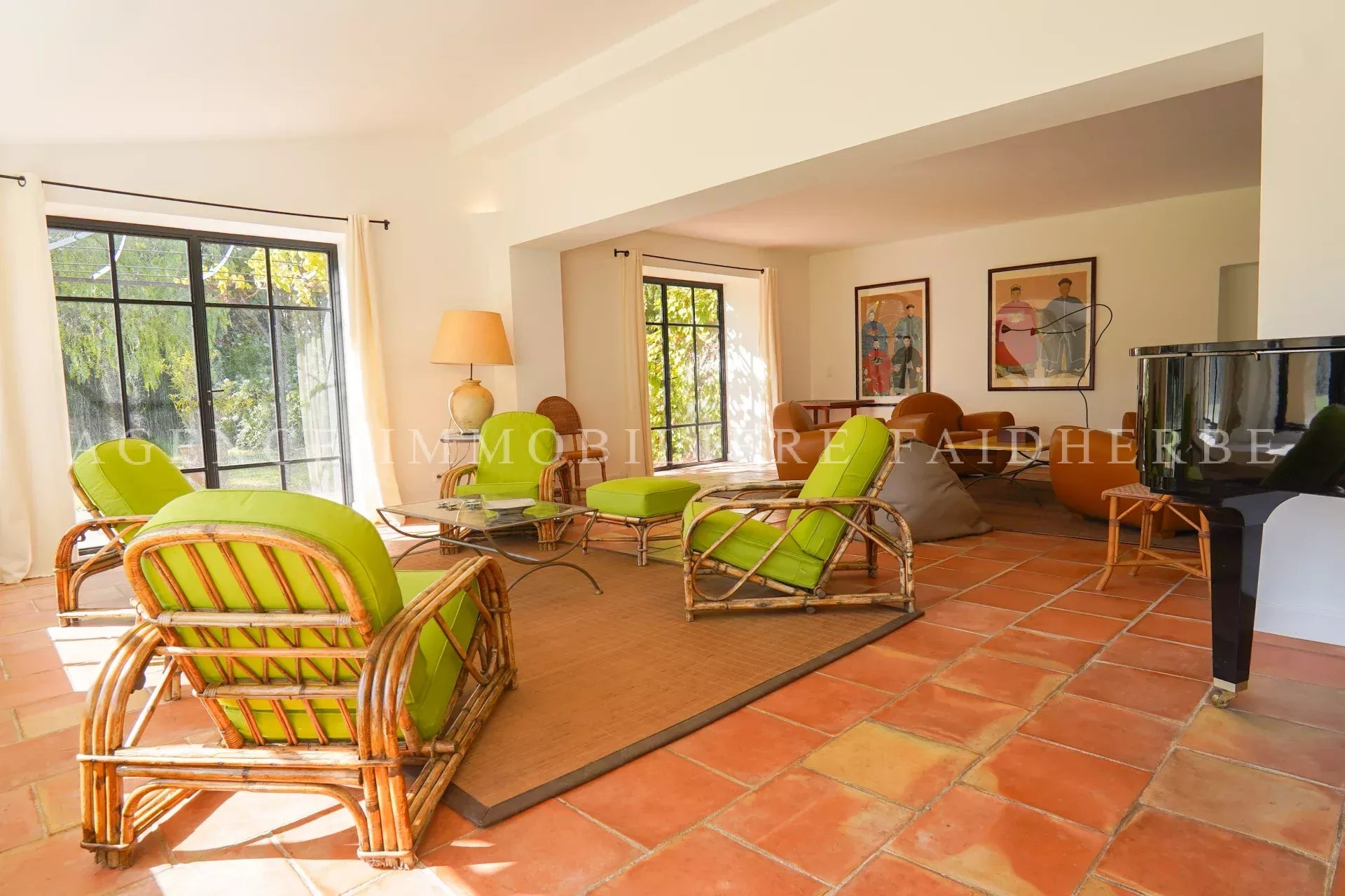 Salon lumineux avec mobilier en rotin et vue sur le jardin.